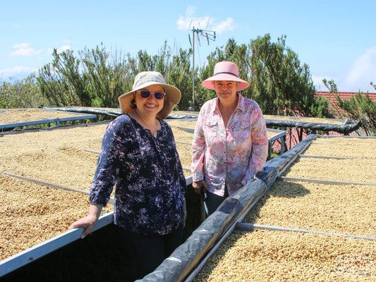 Maricruz (left) and mother, Maria Elena, pose for a photo in front of their raised drying tables at the Monte Brisas green coffee mill in Zarcero, Costa Rica's West Valley region.