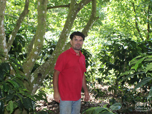 Anibal Erazo poses for a photo beneath the shade trees at his farm in El Cedral, Honduras.