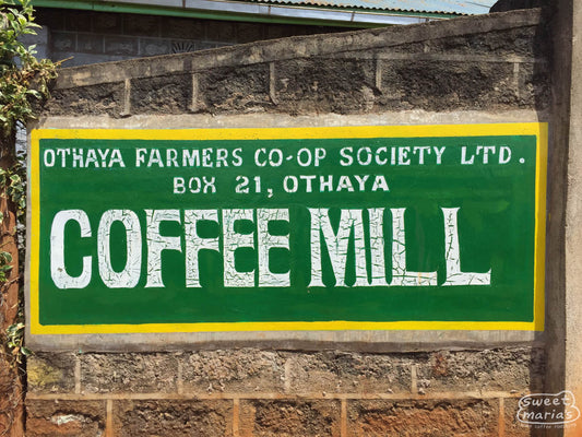 At the Othaya cooperative dry mill, a colorful green and yellow sign reads, 