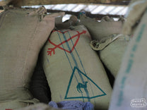Jute bag with an arrow and heart printed on it inside the Kangunu storage warehouse at the coffee factory.