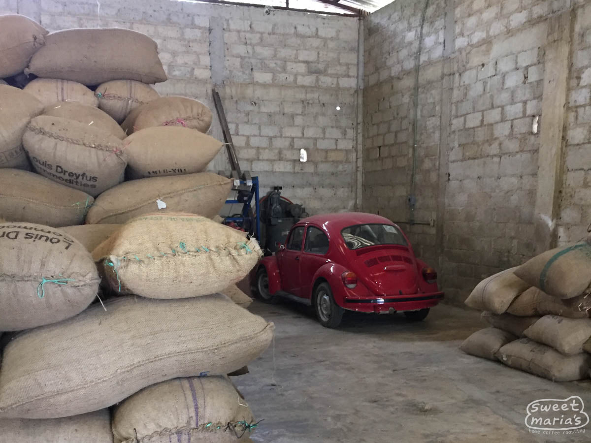 An older red VW Beatle parked inside a coffee warehouse at a coffee association in Chiapas