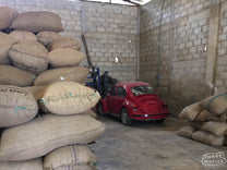 An older red VW Beatle parked inside a coffee warehouse at a coffee association in Chiapas