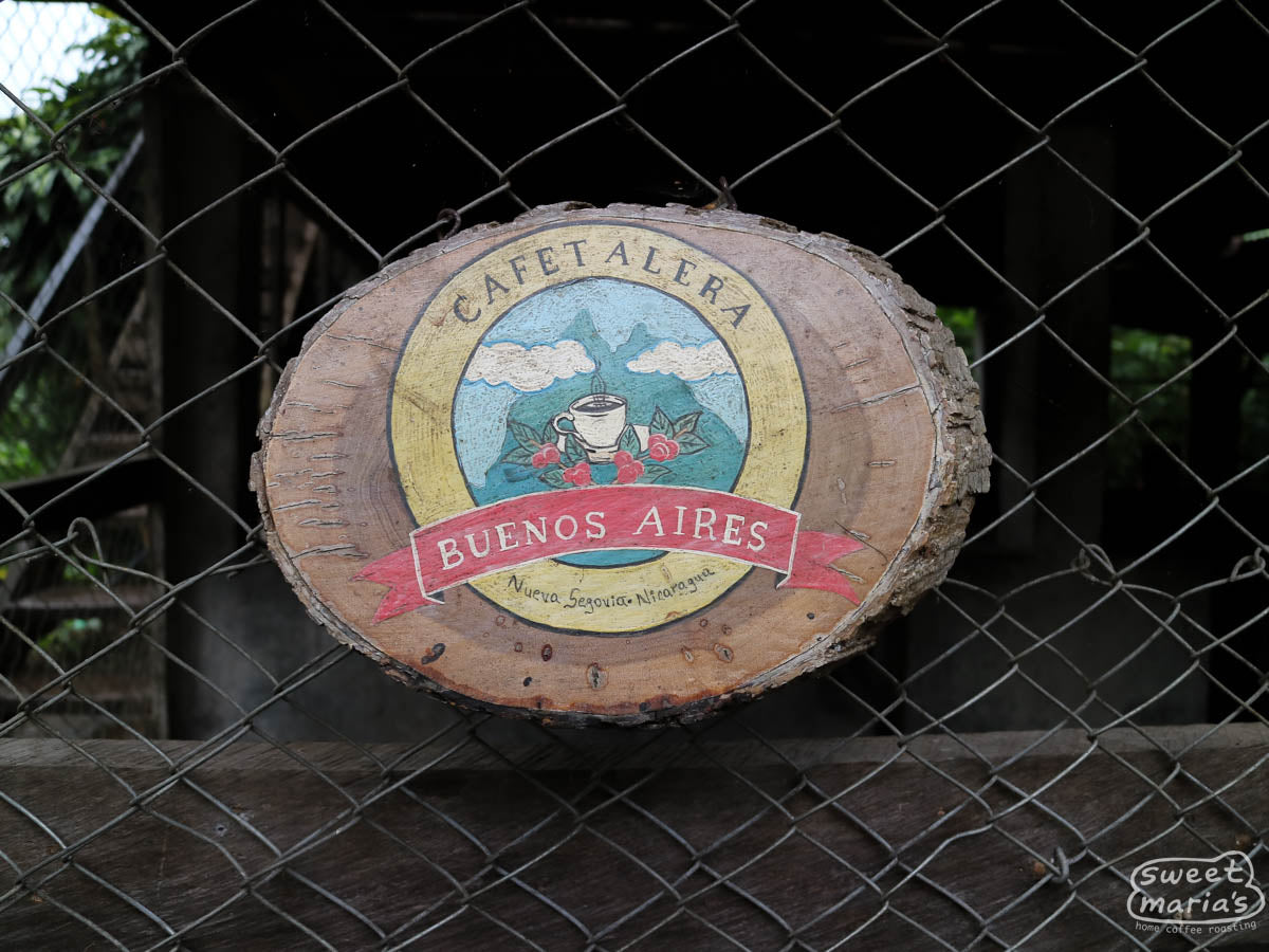 A wooden "Cafetalera Buenos Aires" sign that hangs on the fence near the entrance to the farm. Dipilto, Nicaragua.