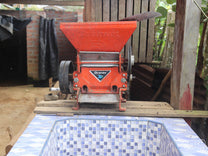 Small motorized pulper that empties into a tiled fermentation tank at a farm in Huabal District, Peru.