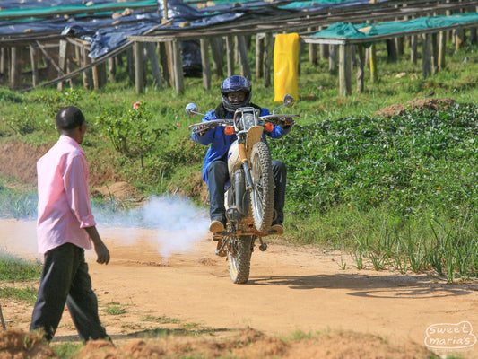 This coffee farmer shows off his wheelie skills on a dirt bike in front of the raised drying beds at the Mutovu coffee washing station in Nyamasheke, Rwanda.