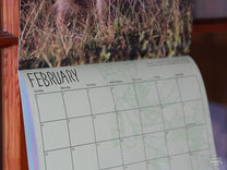 A side-view of a sample page from our 2026 "Dogs" of Coffee Calendar (February).
