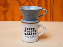 The Kalita MINO Ceramic Dripper is a pour-over style dripper with a flat bottom and three separate drain holes.