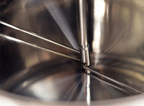 Metal arms attached to a central drive shaft stir the coffee beans throughout the roast