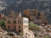Stone city rising from the steep, rocky mountains in Yemen. This is a typical setting in the coffee lands of Yemen, with small outrcoppings of coffee on terraces below, and coffee drying on the rooftops.